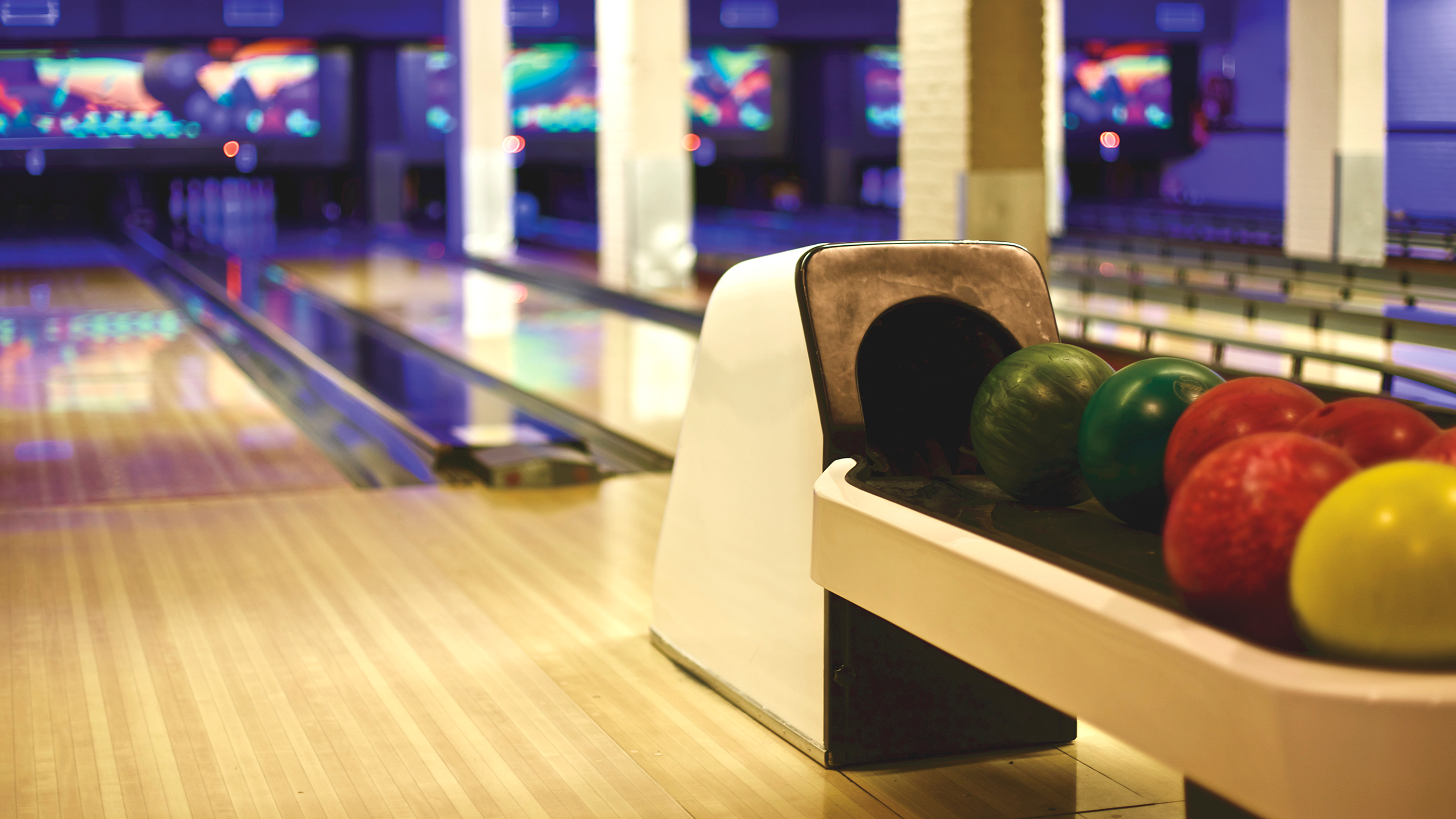 Bowling balls in return rack next to lane